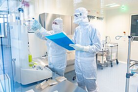 Zwei Personen mit Reinraumoverall, Maske, Handschuhen etc. im Reinraum 