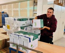 Für mehr Informationen hier klicken Ein Mitarbeiter mit einem Stapel Recyclinpapier