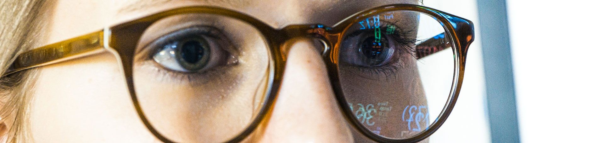 Illustrationsbild einer Frau mit Brille, in deren Gläsern sich der Monitor spiegelt