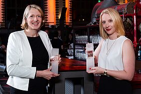 Susanne Ozegowski links und Nora Schorscher rechts halten die gläsernen Preise in den Händen und lächeln in die Kamera. 