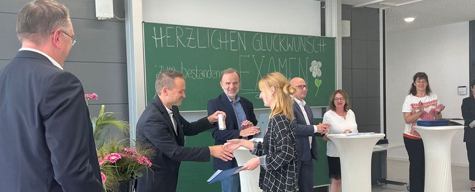 Foto der Zeugnisverleihung mit Lehrern und einer Schülerin im Vordergrund