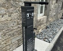 Für mehr Informationen hier klicken Eine schwarze Fahrradreparaturstation vor einer Hauswand