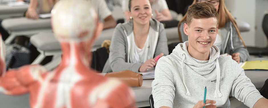 Schülerinnen und Schüler vor einem Muskelmodell des menschlichen Körpers.