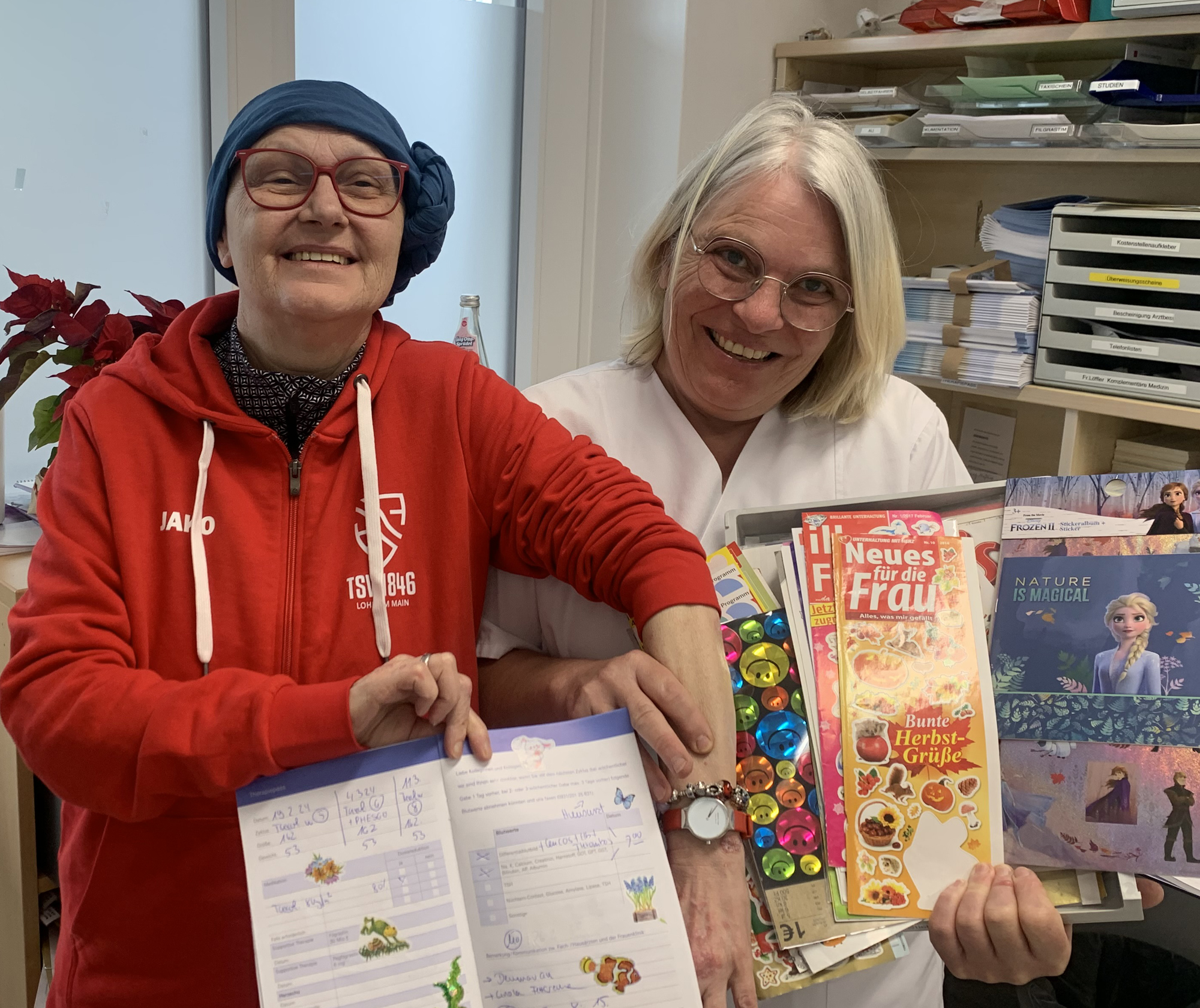 Die Patientin Christina W. (links) und Schwester Katja Ziegler (rechts) präsentieren den mit Aufklebern verzierten Therapiepass.