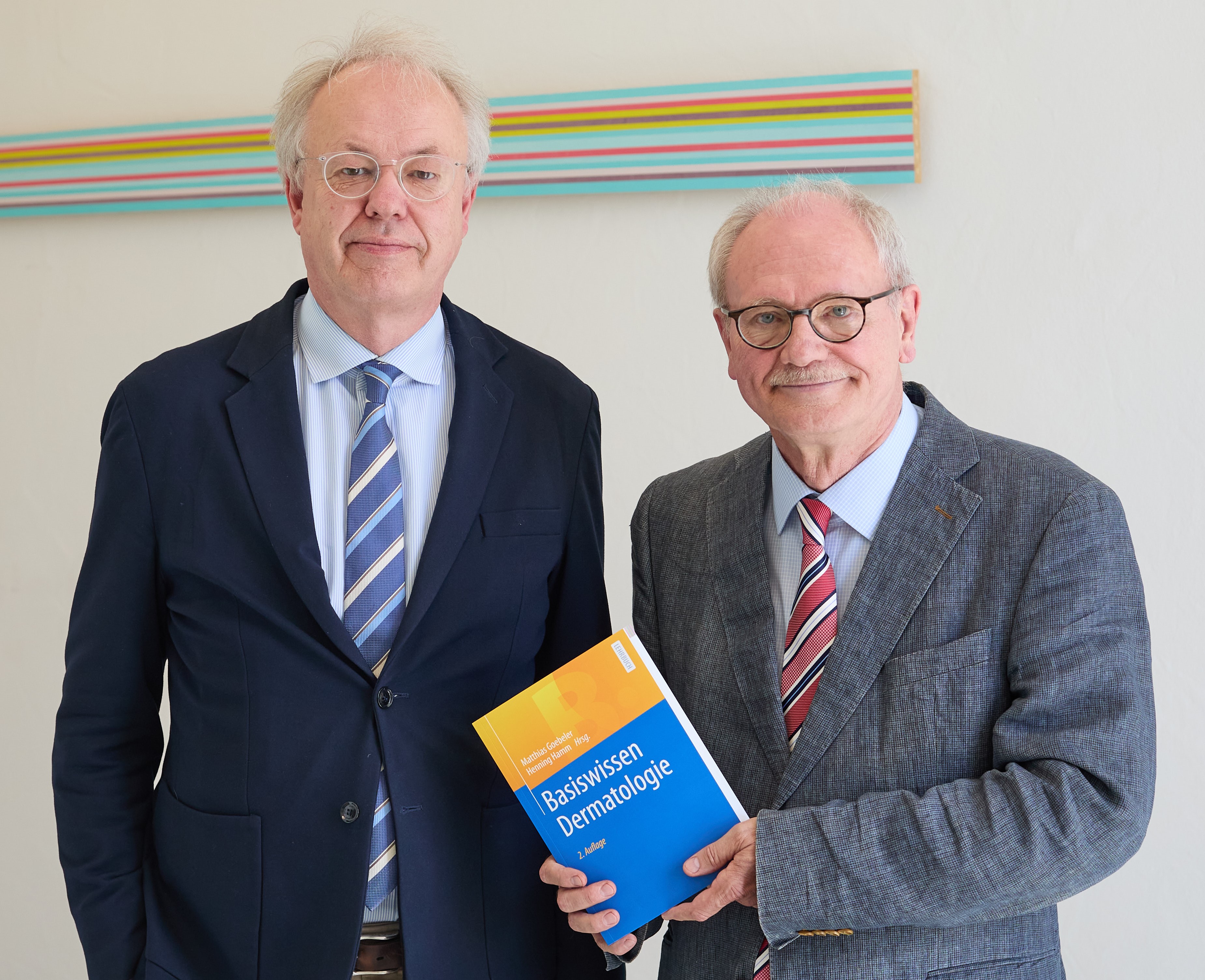 Prof. Dr. Matthias Goebeler (links) und Prof. Dr. Henning Hamm, beide von der Hautklinik des Uniklinikums Würzburg, mit dem von ihnen herausgegebenen Lehrbuch „Basiswissen Dermatologie“. Bild: Hermann Mareth / UKW Prof. Dr. Matthias Goebeler und Prof. Dr. Henning Hamm
